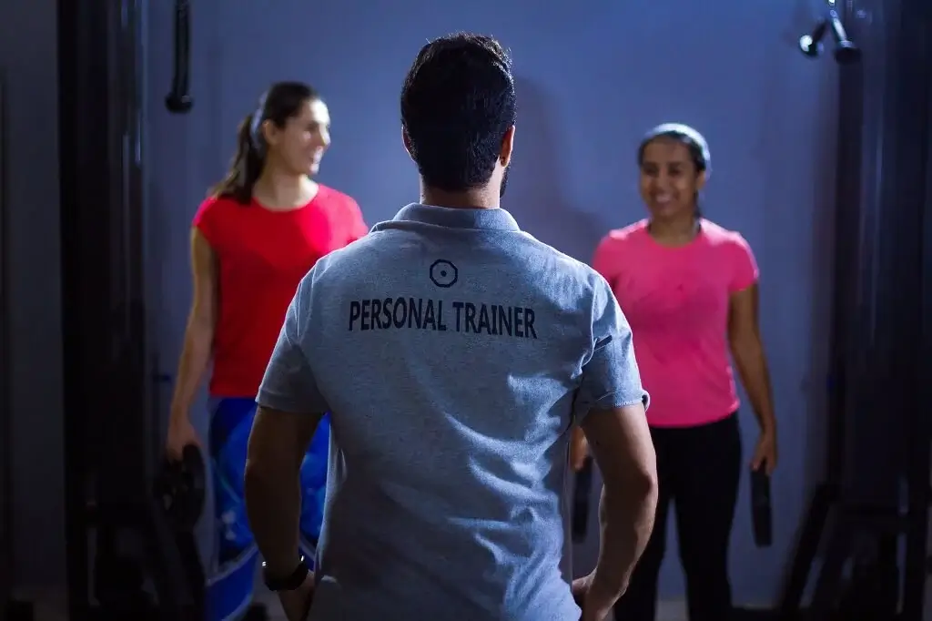A personal trainer coaching two clients through a gym workout providing personalized fitness support.