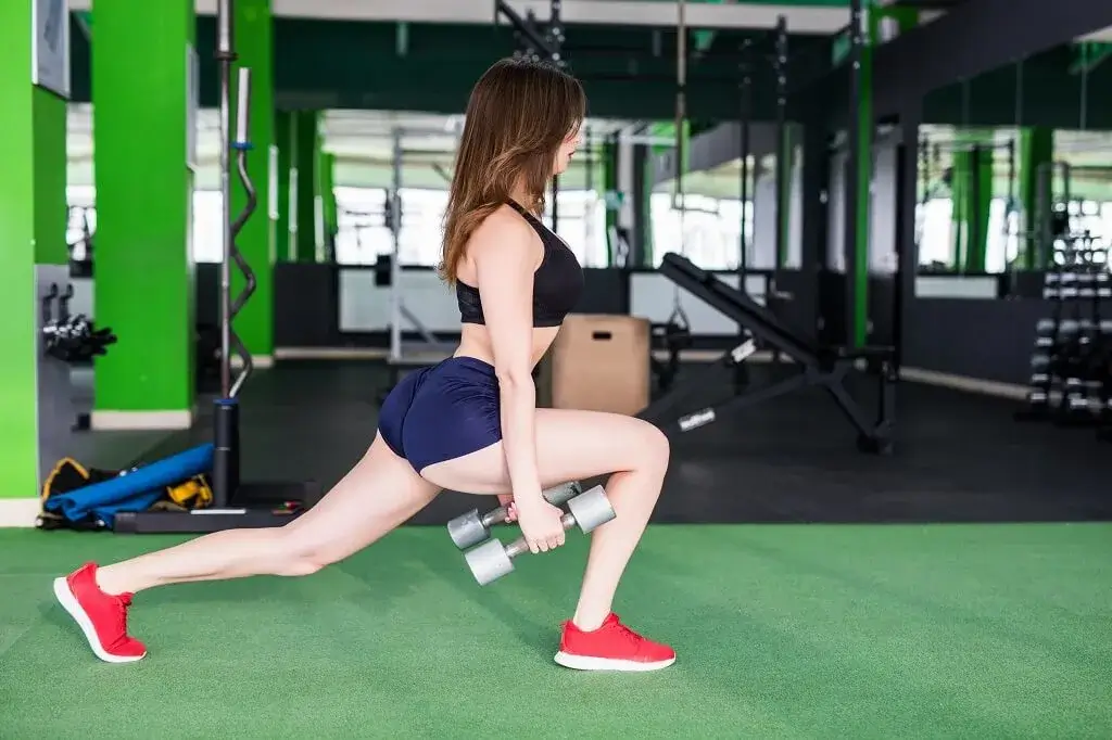 Smiling woman with strong fit body is doing different exercises in modern sportsclub with mirrors Personal-Training-in-Singapore
