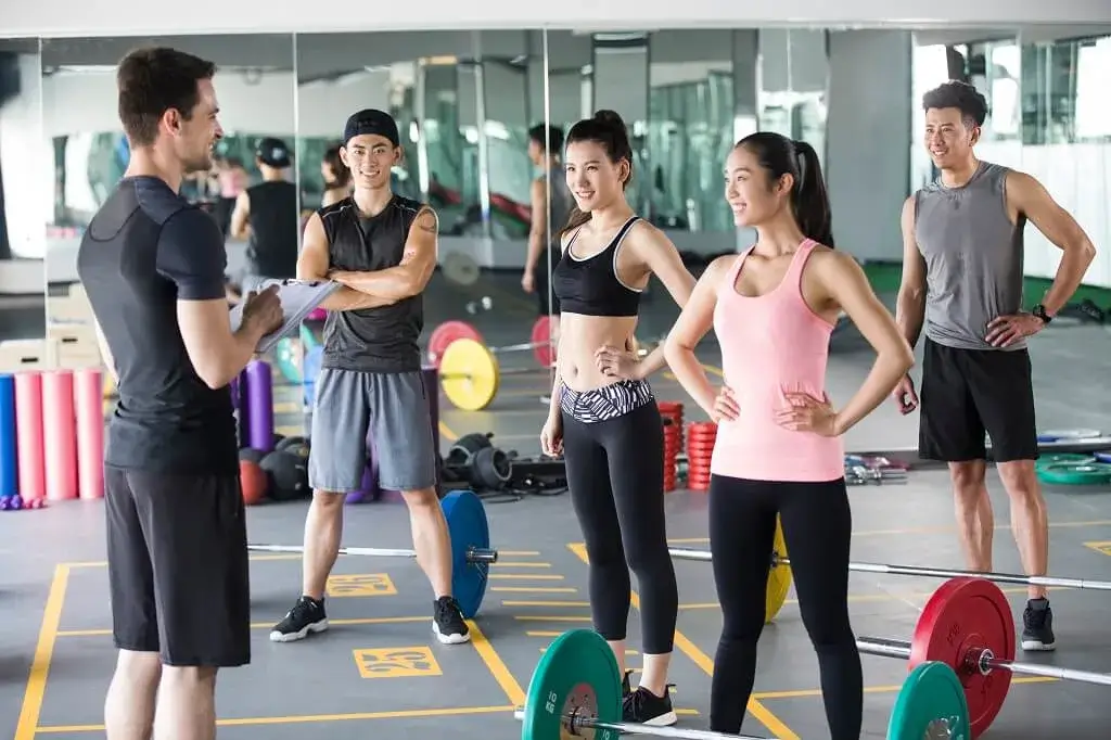 Adults exercising with a personal trainer in a Singapore gym, focusing on guided strength and fitness training.